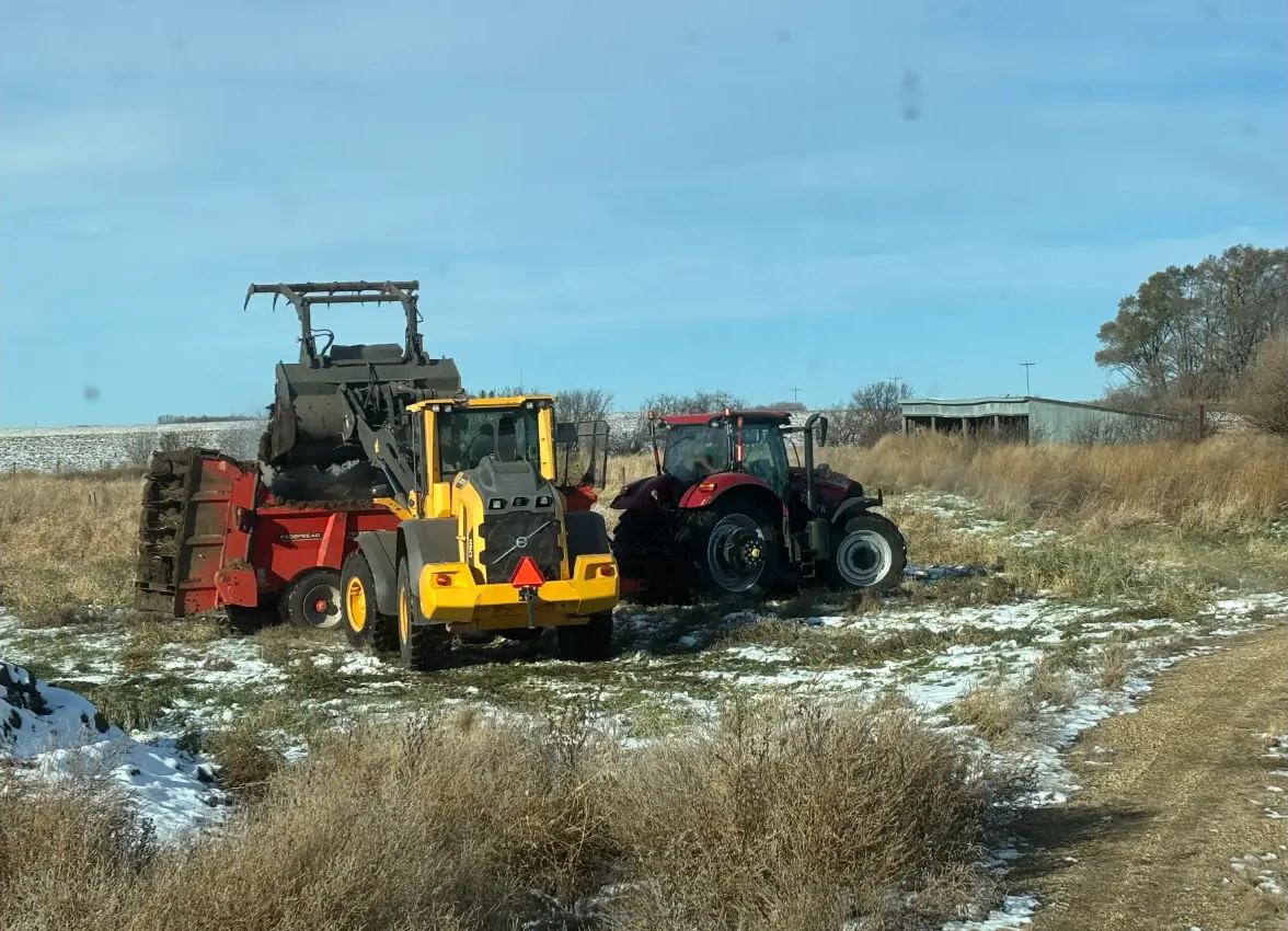 Wheel loader filling a spreader in a field