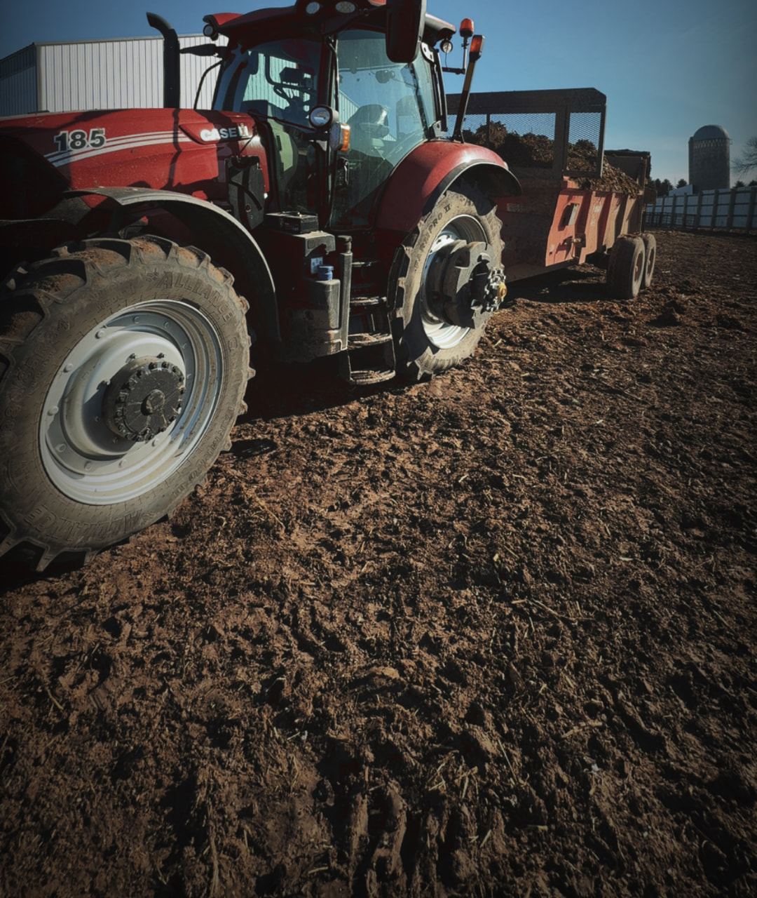 Case IH tractor with a loaded spreader in a yard